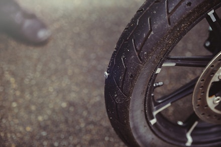 punctured motorcycle wheel, a nail sticks out of the tire, tire fitting