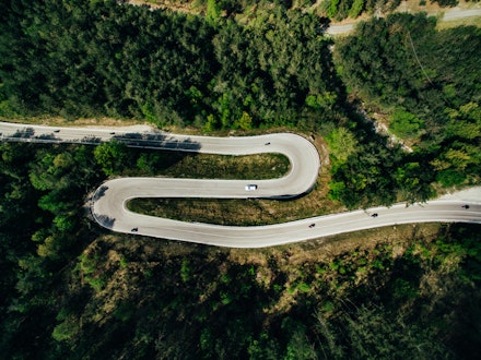 Aerial above view of a rural mountain landscape with a curvy road in Italy.