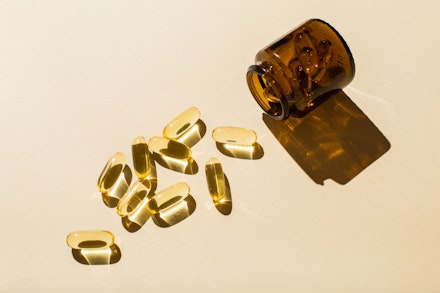 Omega 3 fish oil capsules and a glass bottle on a beige background. supplements and a jar