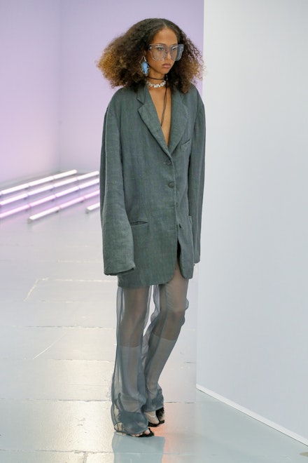 A model wearing a green suit jacket and sheer trousers at Acne Studios SS21 A model wearing a green suit jacket and sheer trousers at Acne Studios SS21