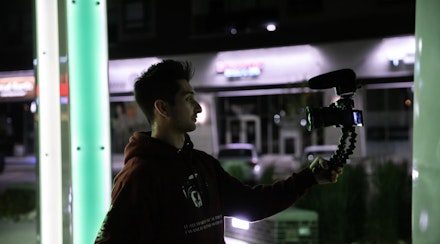 Man recording using camera and Jobi tripod Man recording using camera and Jobi tripod