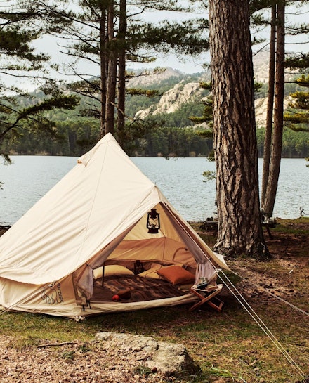 A tent from Nordisk pitched in a forest by a lake A tent from Nordisk pitched in a forest by a lake