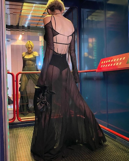 Emma Corrin standing in a lift wearing a sheer dress from Charlotte Knowles Emma Corrin standing in a lift wearing a sheer dress from Charlotte Knowles
