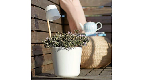 White planter on garden bench with light
