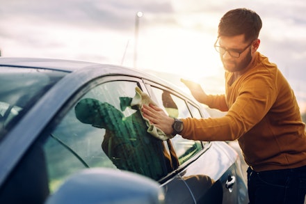 A man cleans a car with a microfibre drying cloth A man cleans a car with a microfibre drying cloth