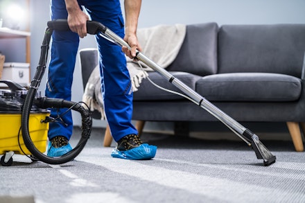 A person using a wet and dry vacuum for cleaning a carpet A person using a wet and dry vacuum for cleaning a carpet