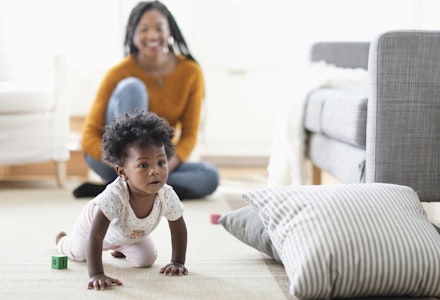 Woman watching baby daughter crawl toward pillow Woman watching baby daughter crawl toward pillow