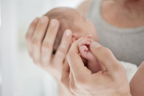 Mother cradling newborn baby's hand Week 5