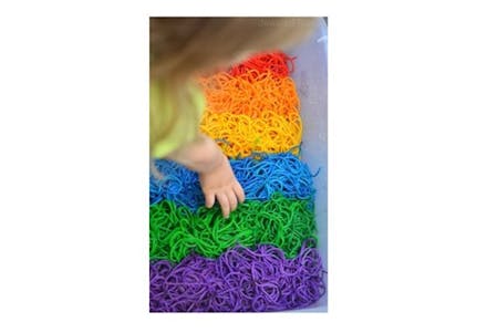 Rainbow noodles child playing with multicoloured laces