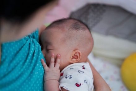 Mother breastfeeding and hugging baby. Asian mom breast feeding her child.Baby hold her hand on face while eating milk before sleeping. Mother breastfeeding and hugging baby. Asian mom breast feeding her child.Baby hold her hand on face while eating milk before sleeping.