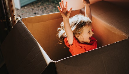 Excited little girl jumping inside a huge Cardboard Box Excited little girl jumping inside a huge Cardboard Box