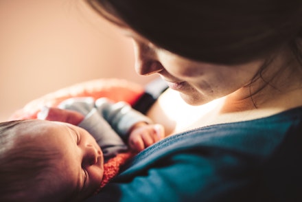Smiling mother looking at her newborn baby daughter. how to hold baby in your arms