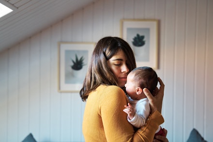 Side view of new mother comforting her newborn while crying. mum holding newborn baby