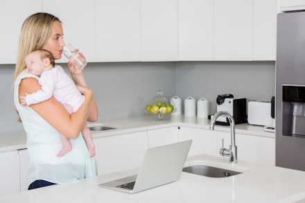 Mother drinking water while carrying baby in kitchen mum drinking water and holding baby