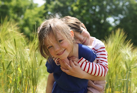 A girl carrying her little brother in a wheat field fostering siblings
