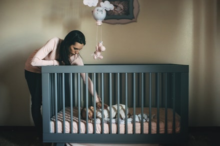 mum comforting baby in cot