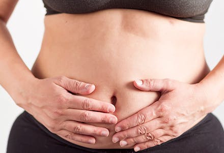 1) A bloated or distended tummy Women holding stomach