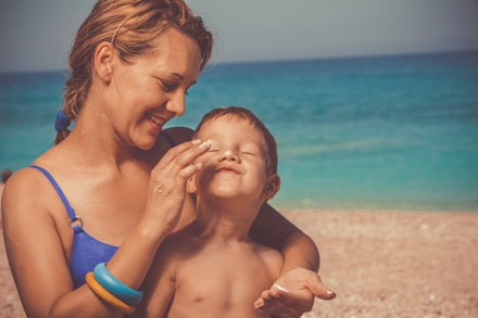 Mum putting suncream on son