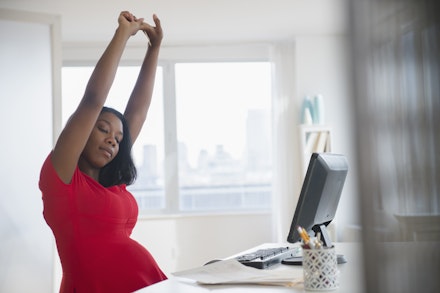 pregnant woman stretching at desk