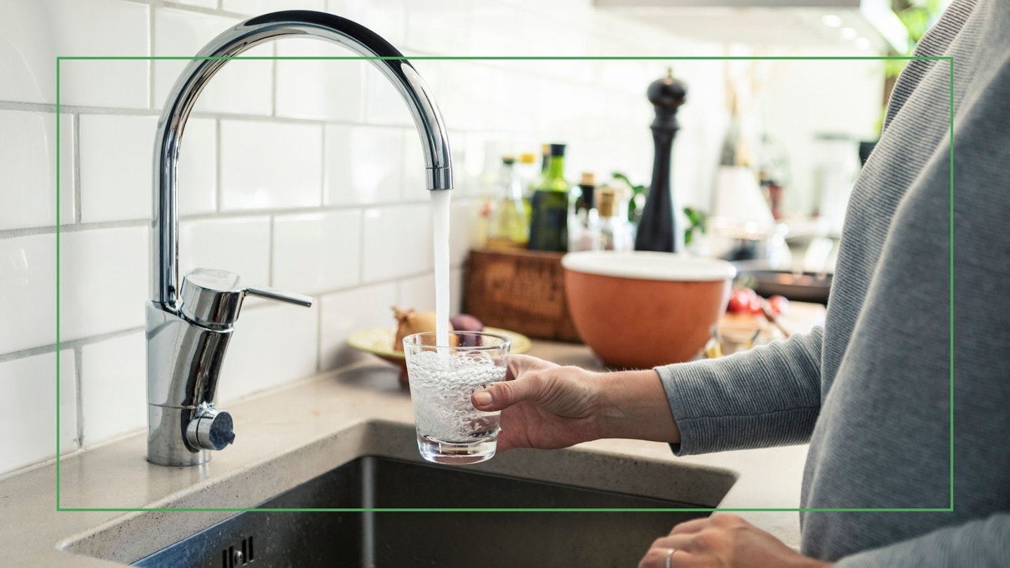 Midsection of woman holding glass under faucet in kitchen - stock photo