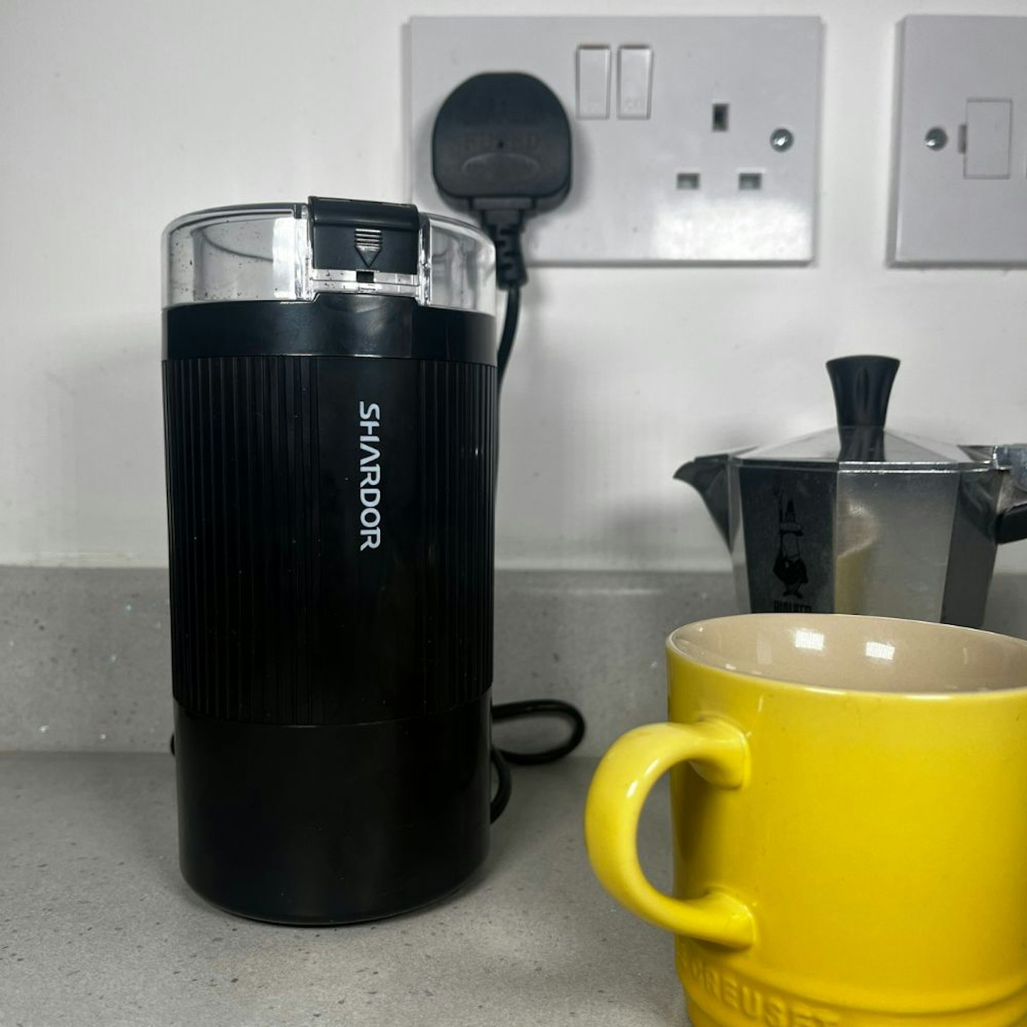 The SHARDOR Electric Coffee Grinder on test, a yellow mug sits next to it.