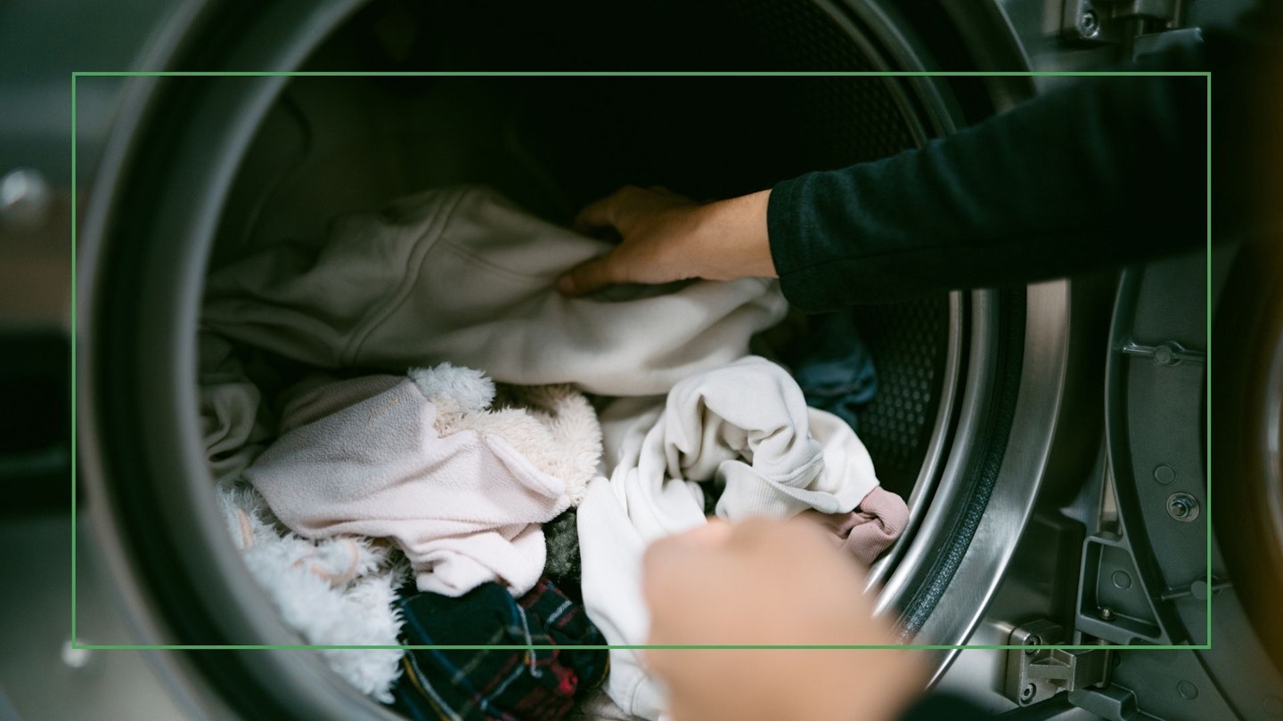 Young woman hands putting her clothes in a heat pump tumble dryer.