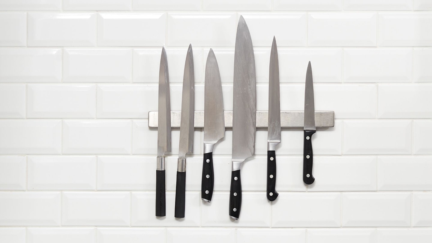 Six Japanese knifes hanging on white wall tile