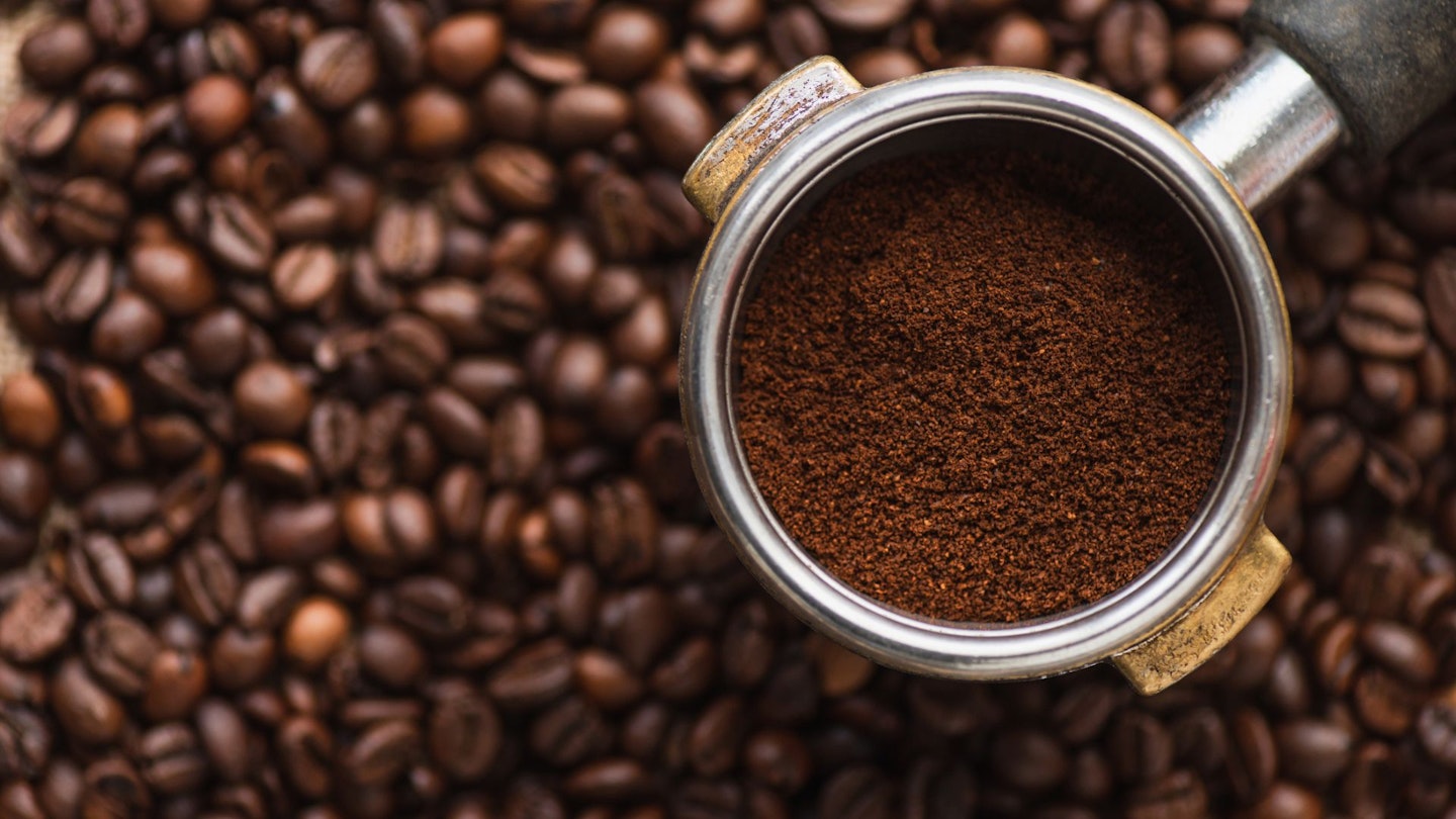 top view of ground coffee in portafilter on coffee beans background
