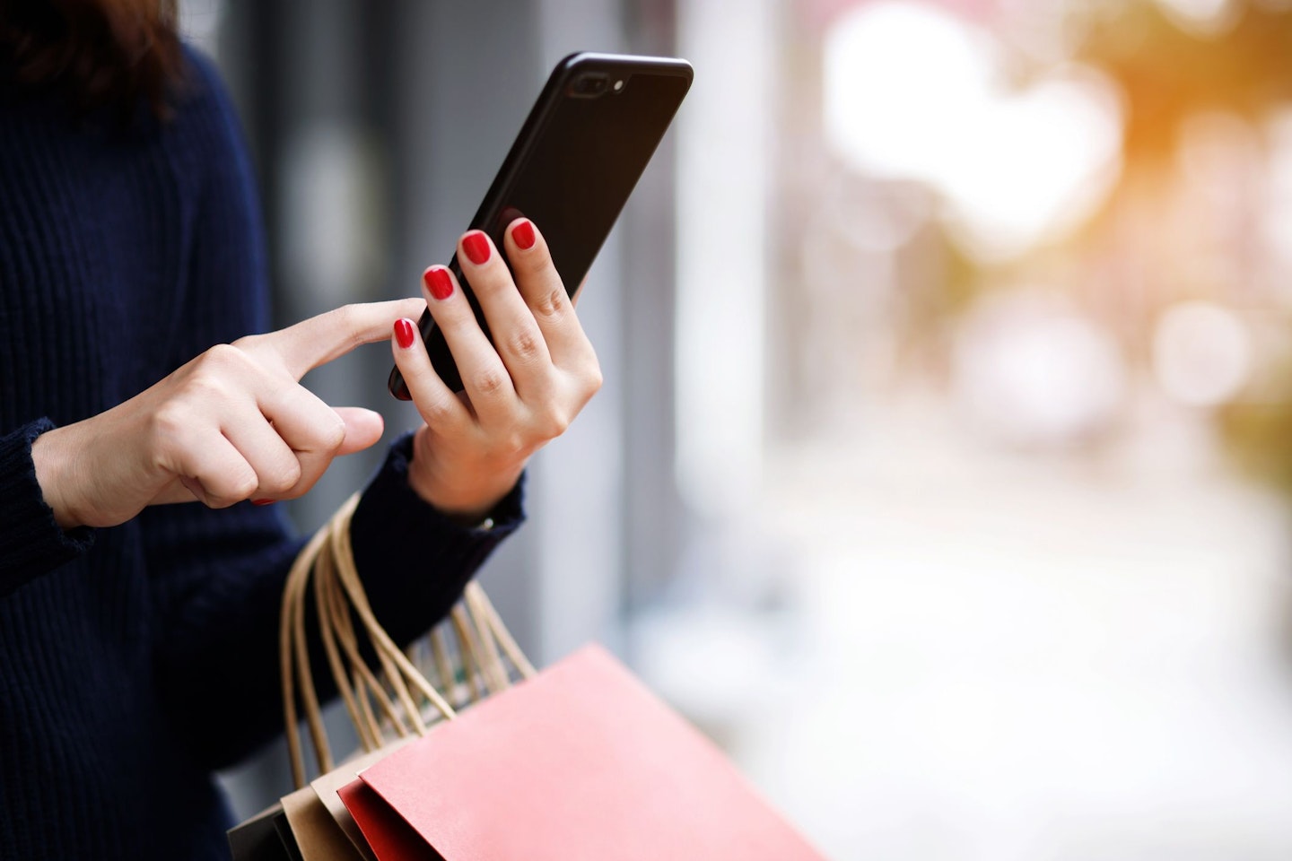 Female hands holding a smartphone and shopping bags