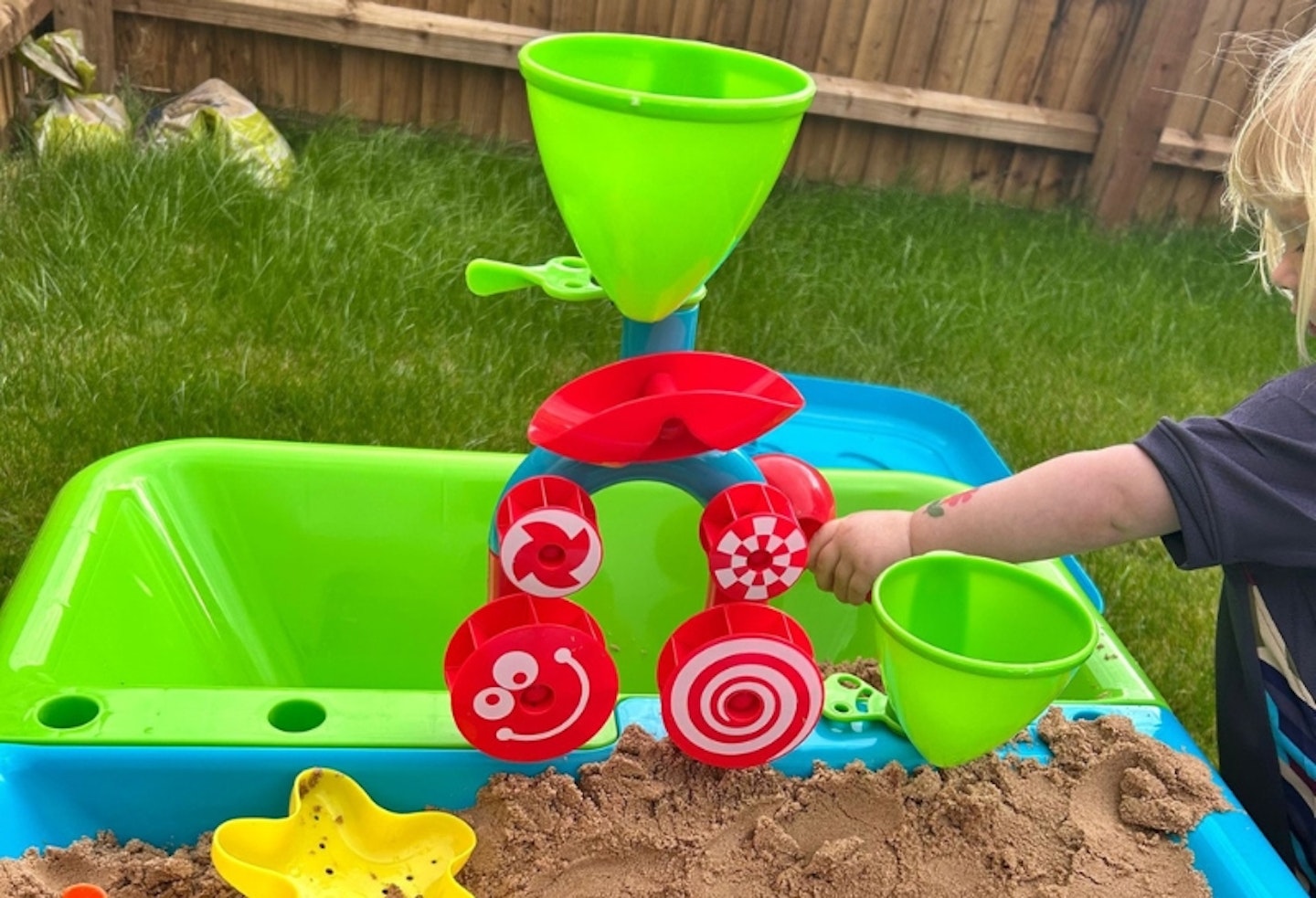 a child playing with the Early Learning Centre Sand and Water Table and toys in the middle of the table