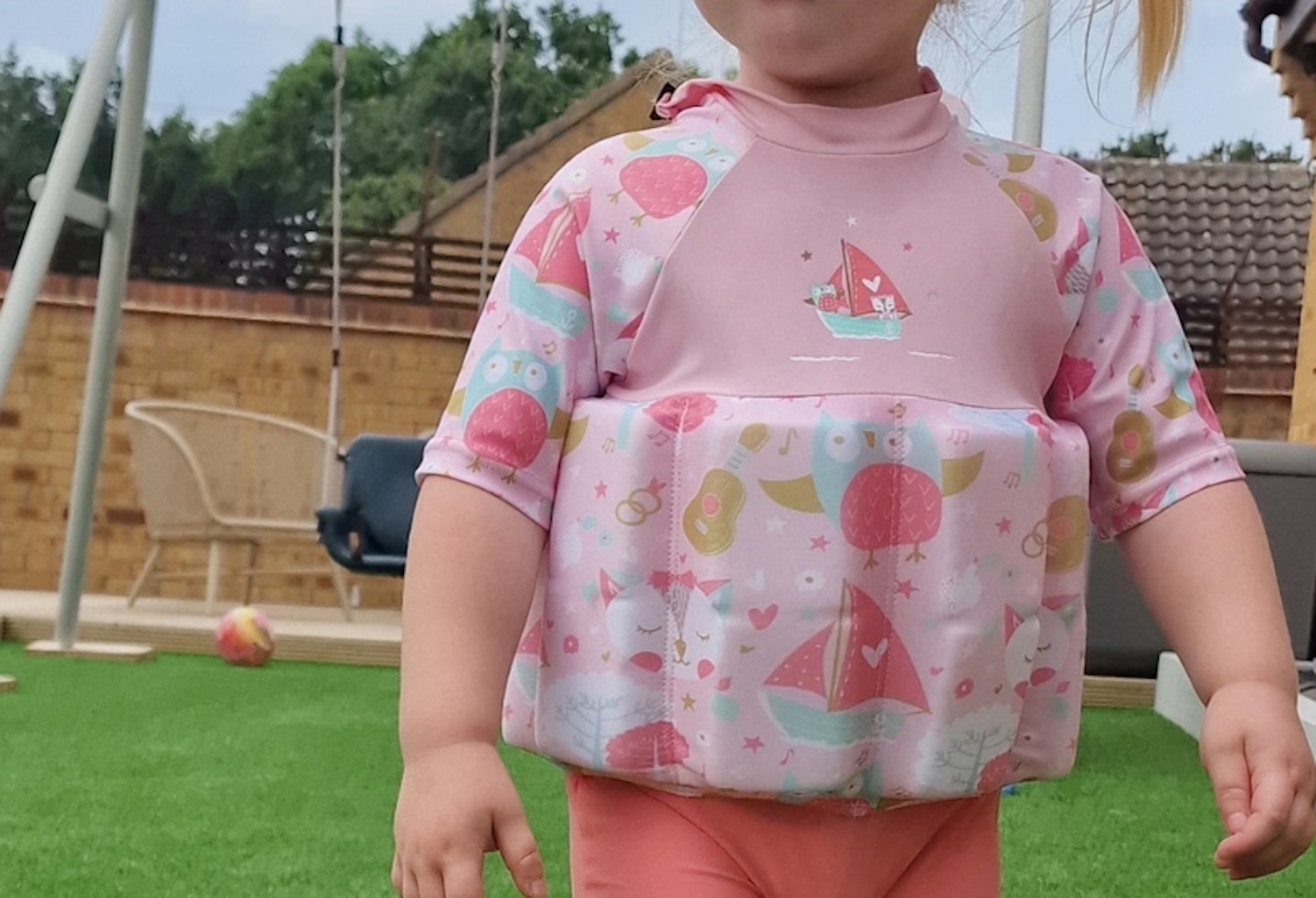 close up shot of a child wearing the Splash About Sun Protection Float Suit, showing the pattern and foam pads of the top