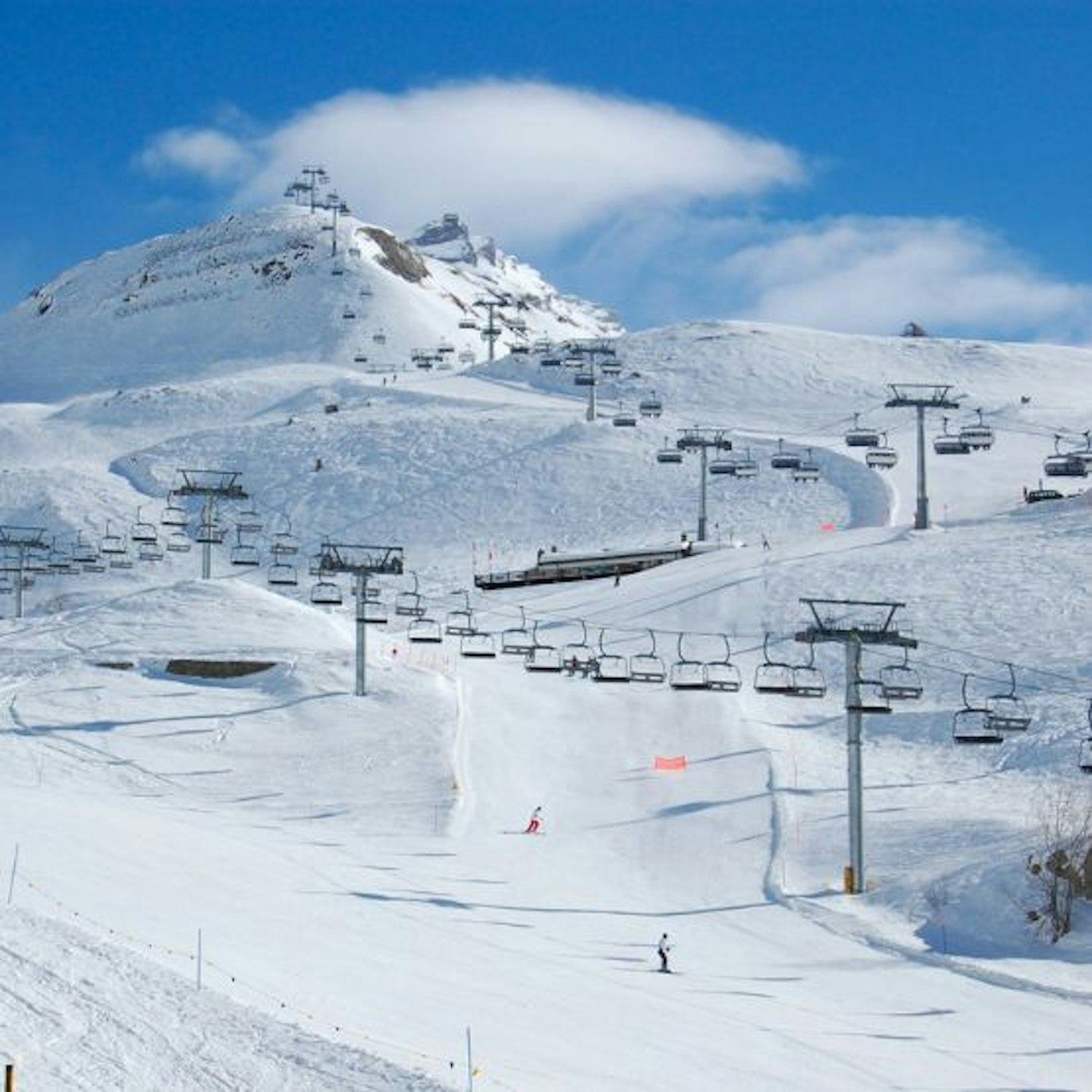 Skiers on the slopes of Cervinia with cable cars behind
