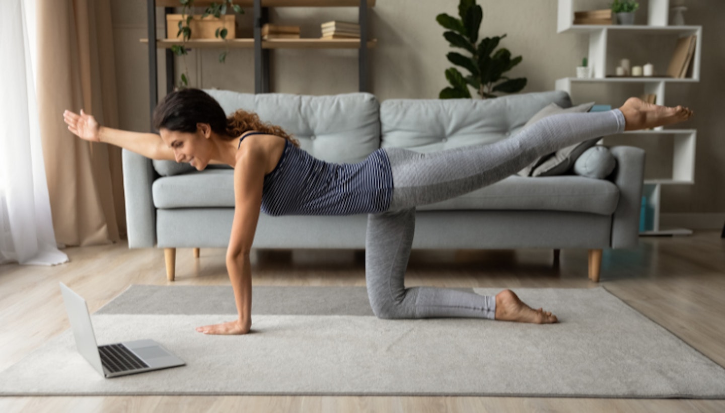 Side view smiling woman practicing yoga online, using laptop