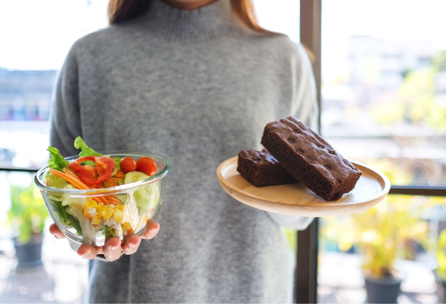 A woman holding and choosing food to eat between a plate of