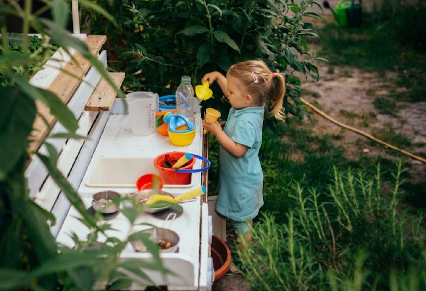 Child playing in the garden with her outdoor mud kitchen