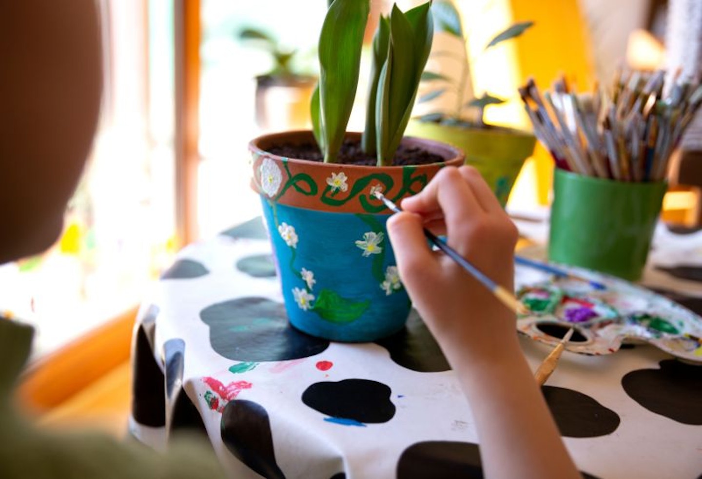 Child's hand painting patterns on a terracotta plant pot