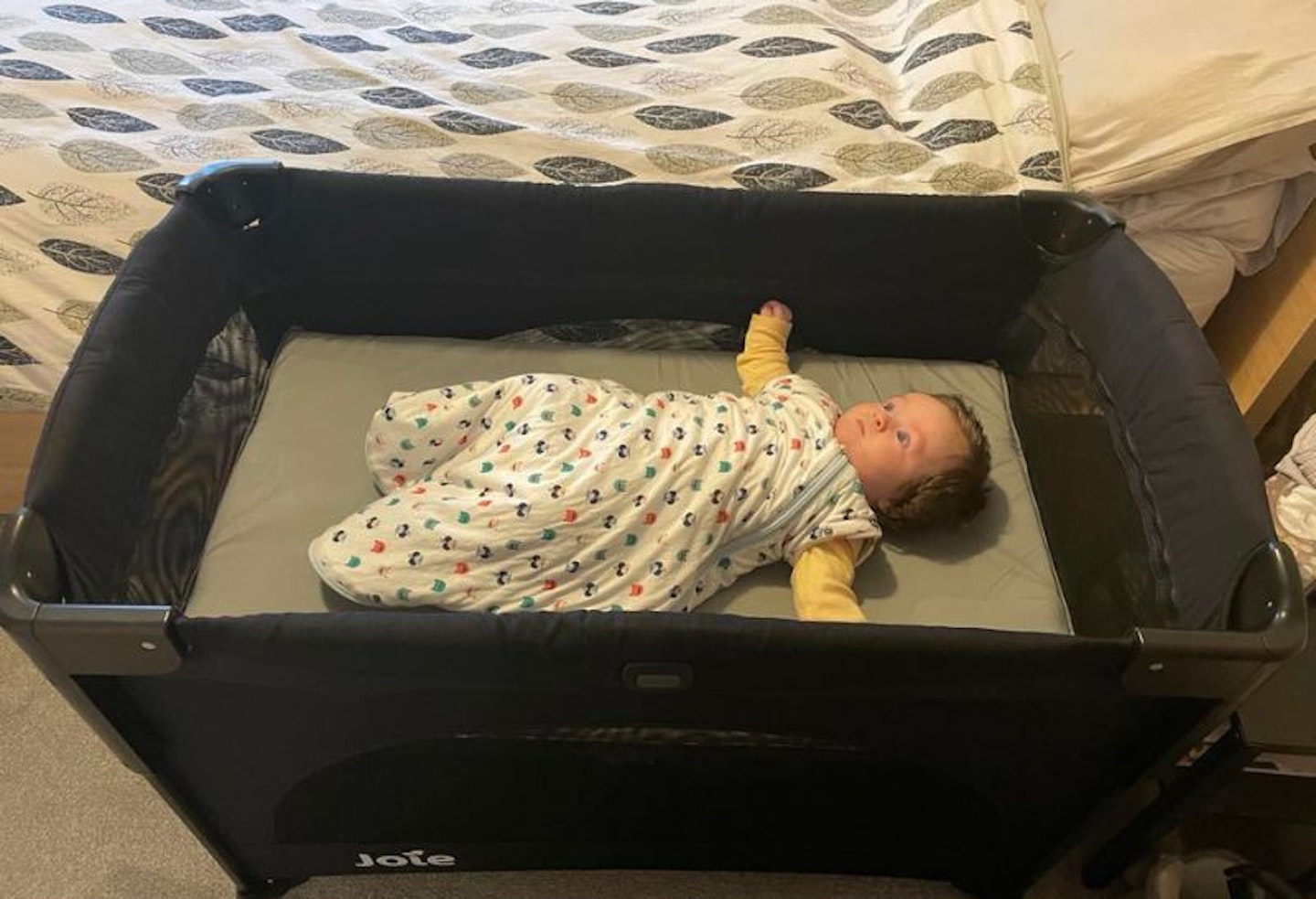 A baby in the Joie Kubbie sleep travel cot