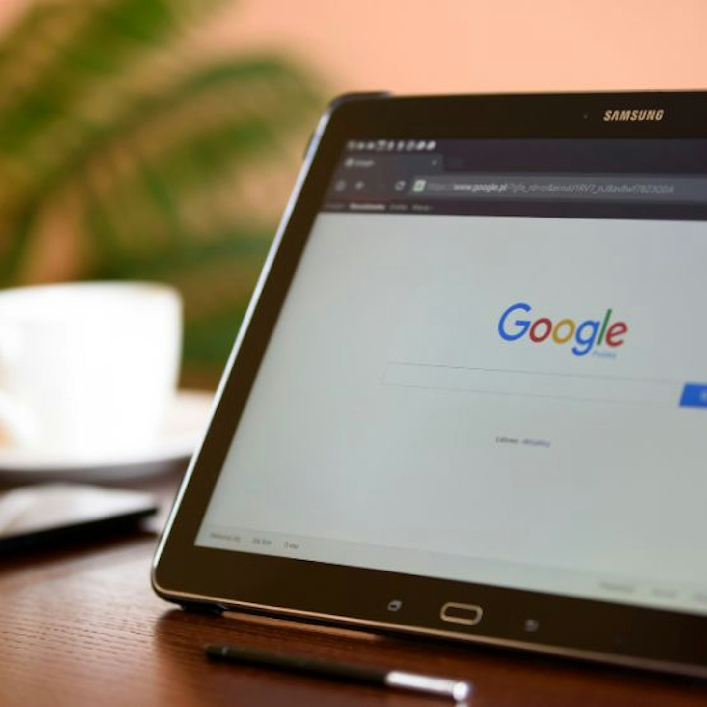 A laptop open on a Google search screen with a tea cup in the background 