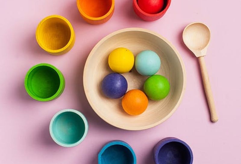 A bowl full of coloured balls with coloured pots around the edge for sorting colours