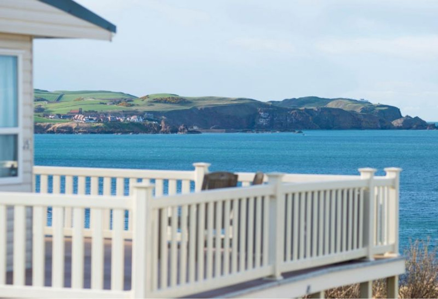 The view of the sea and land beyond with a holiday caravan and balcony in front