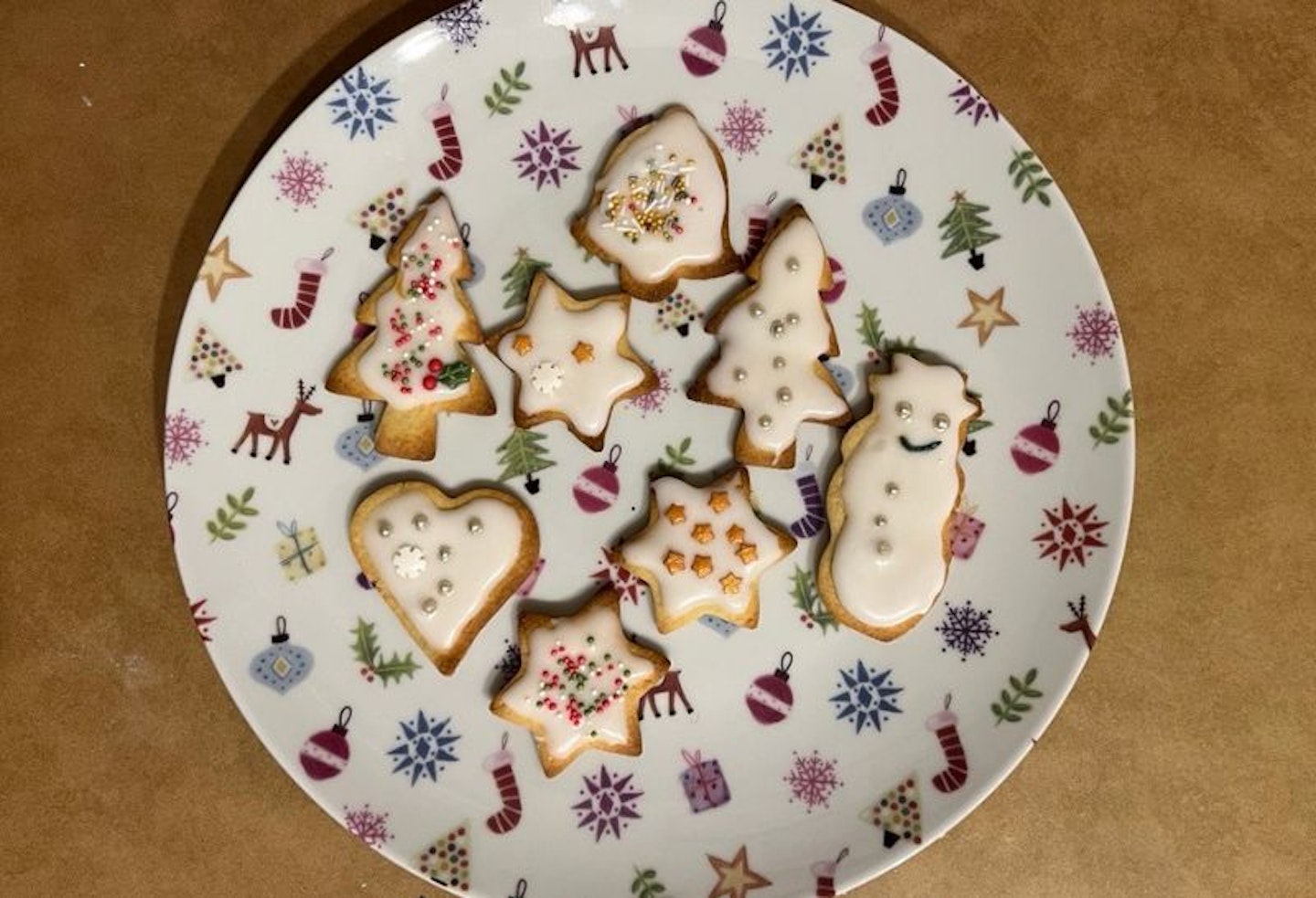 A christmas plate of christmas iced biscuits, including snowmen, stars, bells and hearts