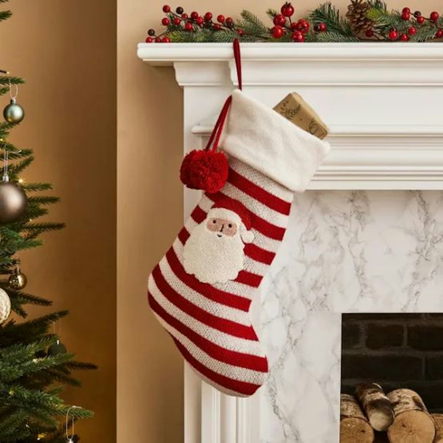 A red and white stocking on a fireplace with a Father Christmas face embroidered on