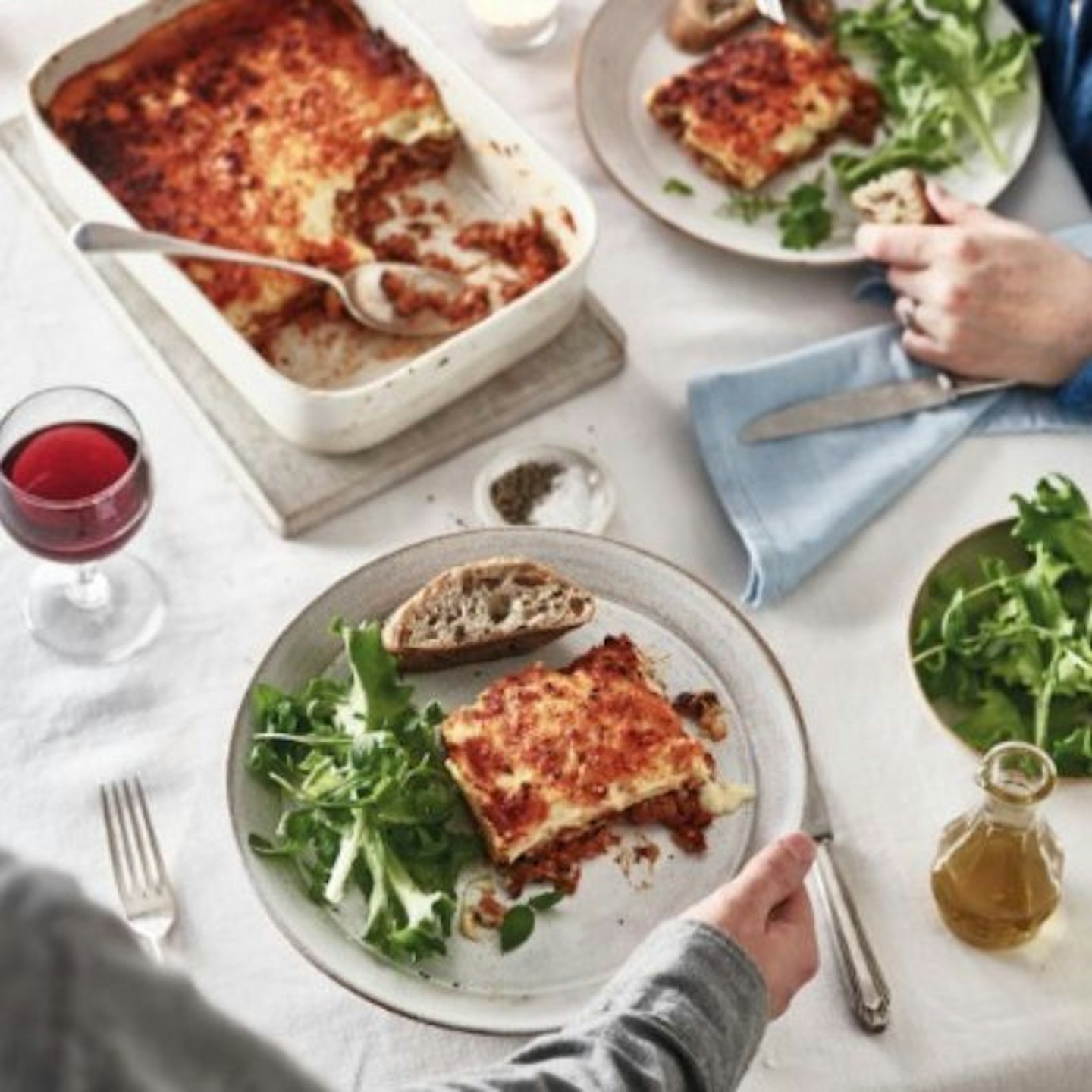 A table with a lasagne from COOK and two plates with green salad