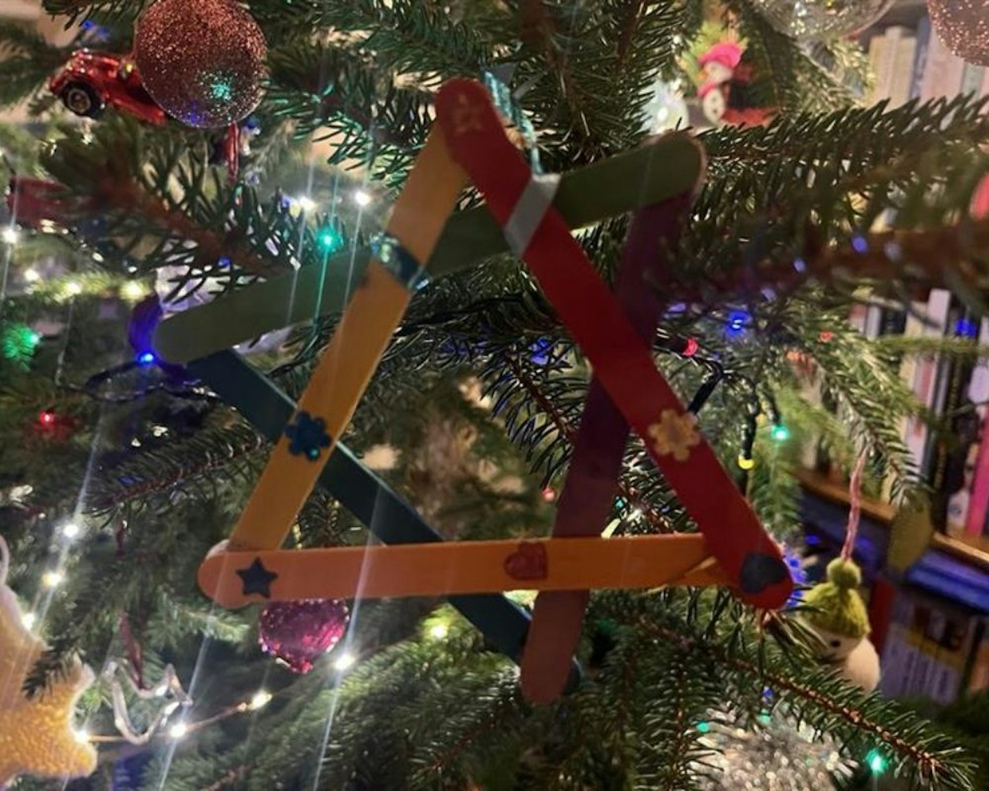 A lollypop stick star hanging on a Christmas tree