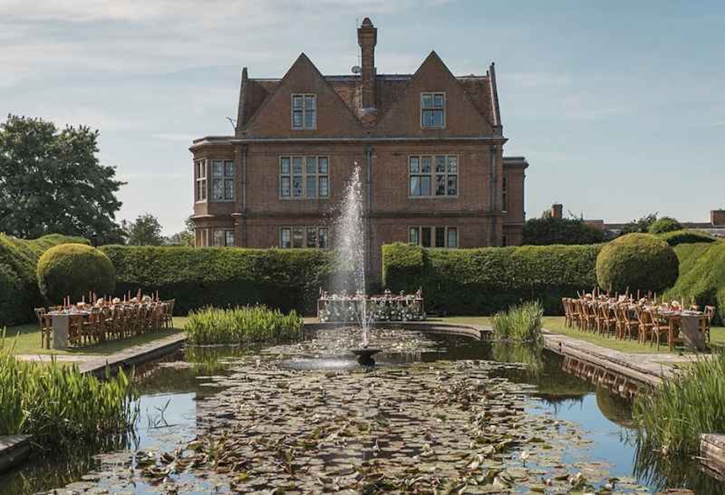 A view of Horwood House across the lily pond with tables set up on either side