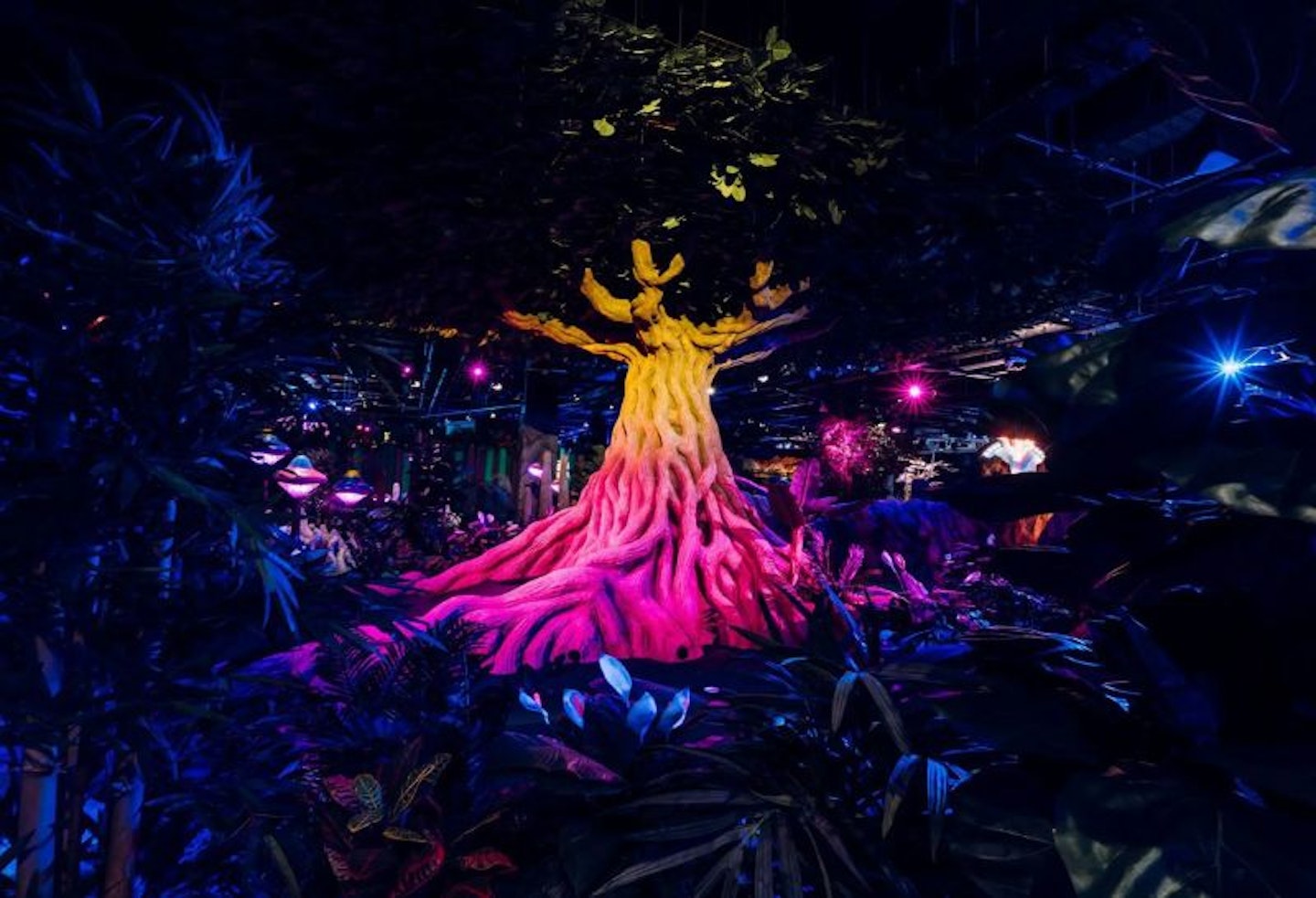 A tree at Treetop Adventure golf, Cardiff, lit up with pink and yellow lights