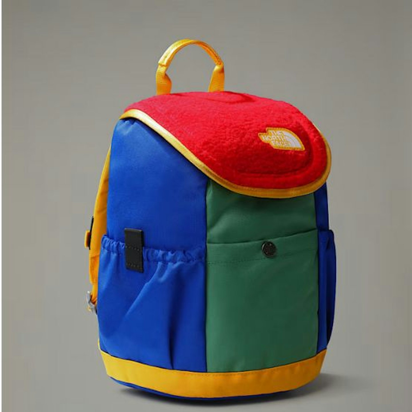 A North Face Mini Explorer backpack in red, green and blue with a yellow handle and base