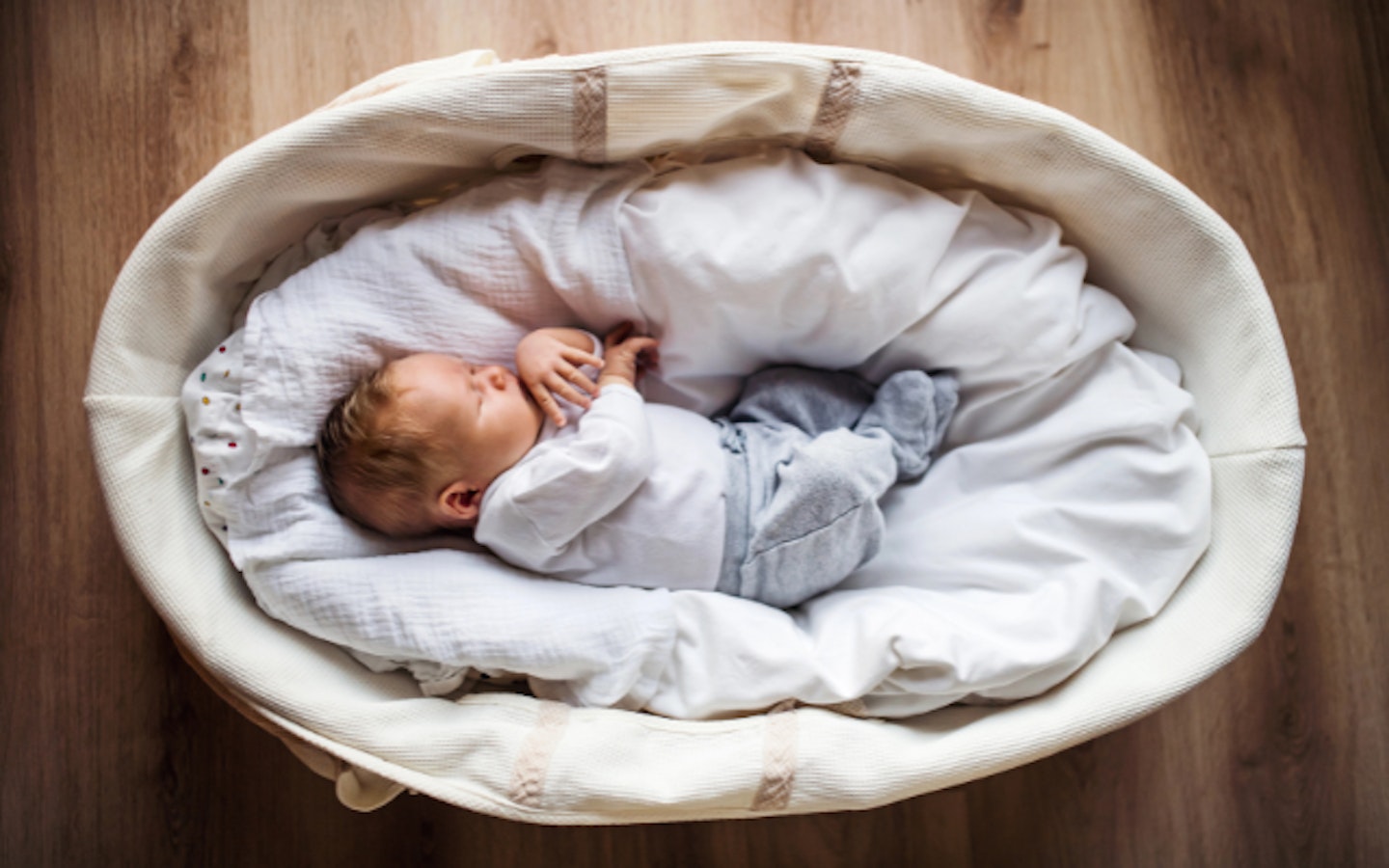 baby lying asleep in moses basket