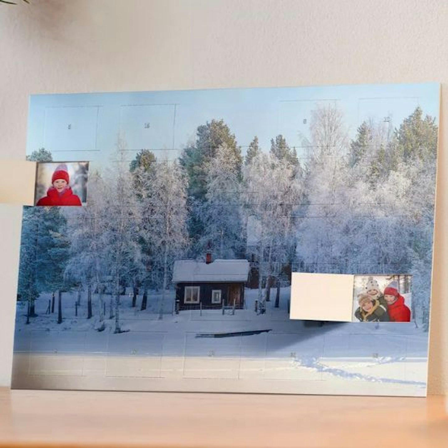 A photo advent calendar with a snowy scene and a couple of doors open to show more photos