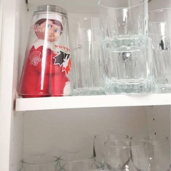 Elf in a glass on the glass shelf in the cupboard